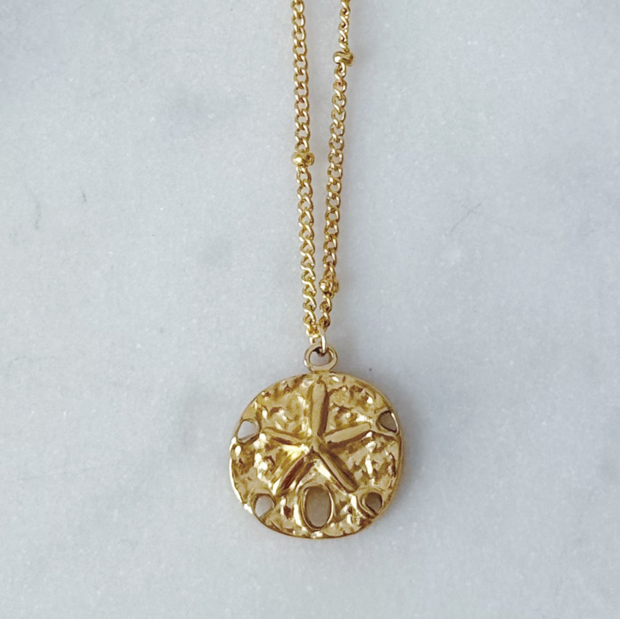 Gold sand dollar necklace